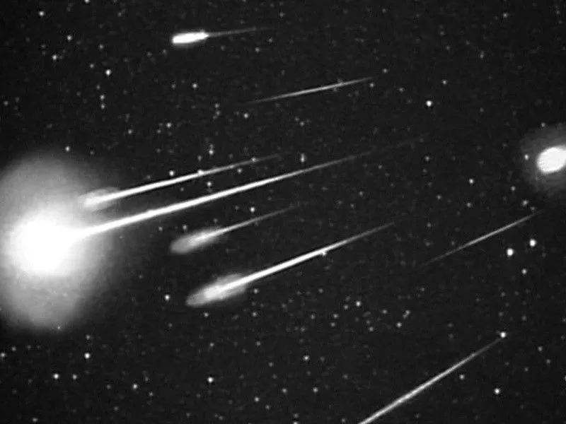 black and white image of meteors on a dark sky
