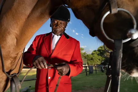 Wearing his national title show jumping jacket, Mafokate checks the reins before mounting his horse at a local competition in the township.