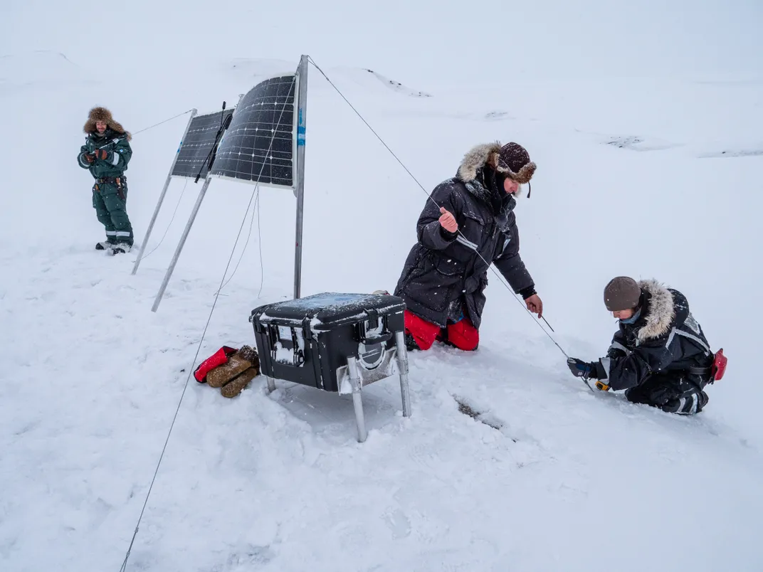 Researchers in snowy landscape setting up equipment