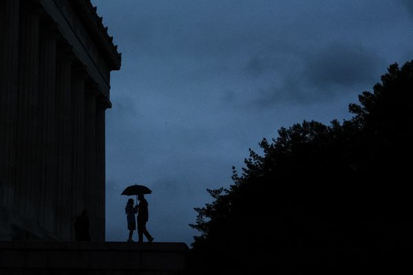 Silhouetted couple under an umbrella at the Lincoln memorial thumbnail