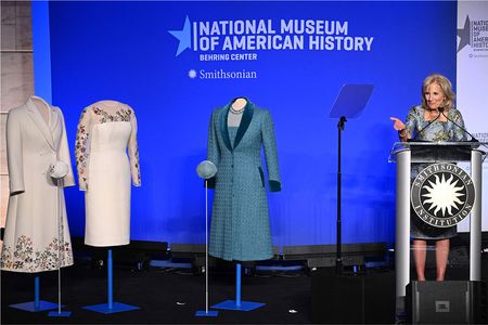 Jill Biden addresses a crowd at the Smithsonian&#39;s National Museum of American History on January 25. Inaugural ensembles by Gabriella Hearst (left) and Alexandra O&#39;Neill (right) stand next to her.