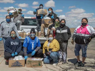Volunteers with the Navajo & Hopi Families Covid-19 Relief Fund distribute food and other essential supplies to isolated communities and farmsteads on the Navajo Nation and Hopi Reservation. As part of the Smithsonian's virtual program 24 Hours in a Time of Change, Shandiin Herrera (Diné)—seated on the left, wearing a Duke University sweatshirt—describes how this grassroots response to the COVID-19 pandemic came together last spring and shares her experiences as the fund's volunteer coordinator in Monument Valley, Utah. (Photo by Karney Hatch) 