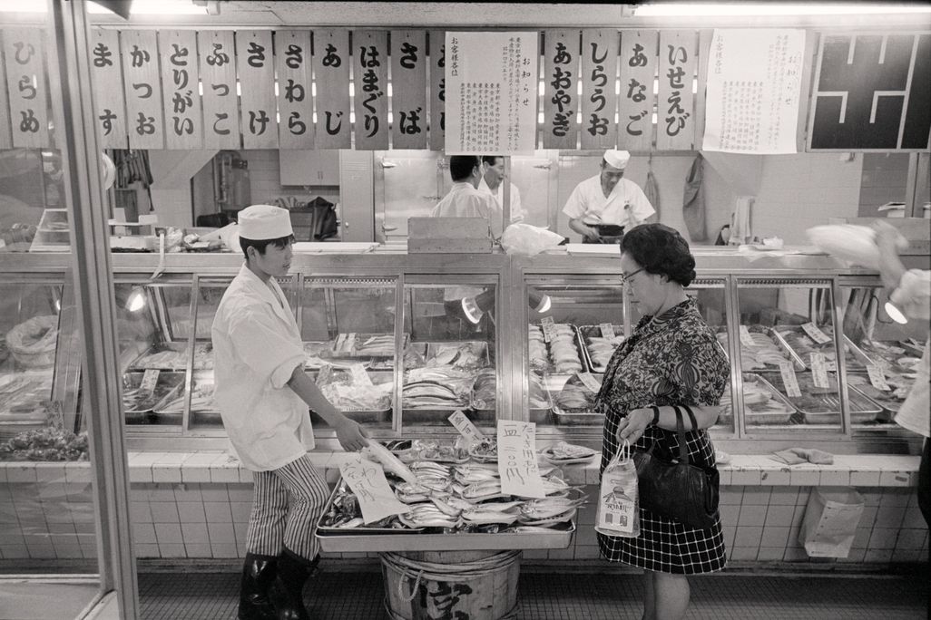 A woman seems hesitant about buying fish at a shop in Tokyo in 1973