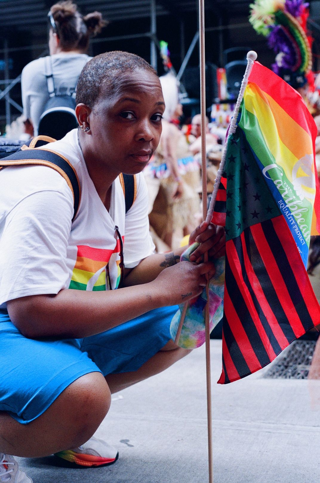 a person in a Pride parade holds up some flags