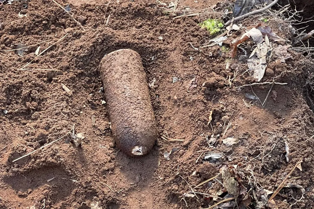 rusted conical artillery shell covered in mud, view from top