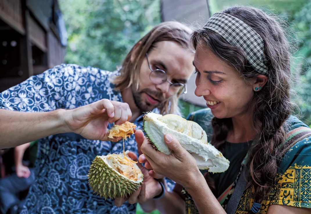 a couple look closely at a Durian fruit