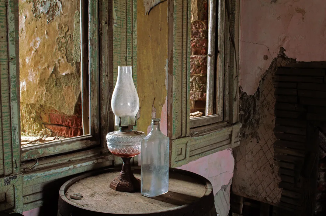 13 - An empty bottle and a kerosene lamp sit atop a barrel in a time-worn room at Fort Adams.