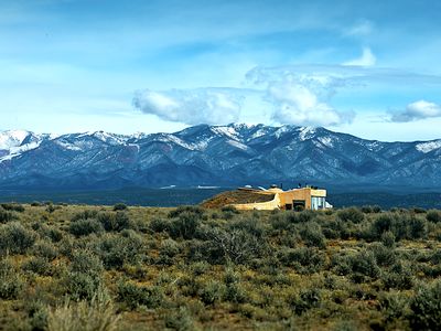 An earthship seems to rise out of the high plains at the foot of the mountains near Taos, New Mexico.