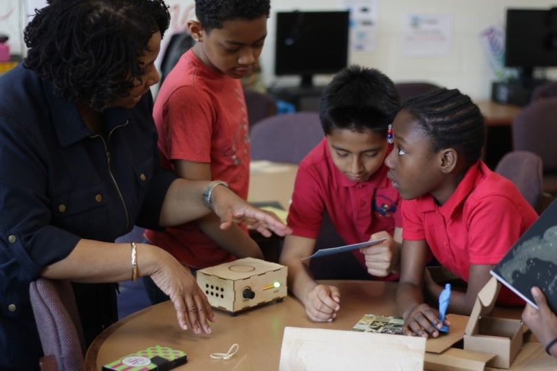 Teacher and three elementary students using Traveling Trunk content in the classroom