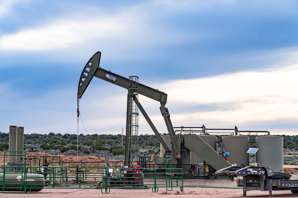 A conventional horsehead oil well pump jack unit and storage tank battery on an oil well site in Utah