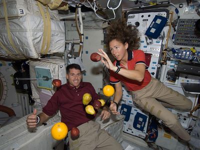 Astronauts Shane Kimbrough and Sandy Magnus play with floating food during the STS-126 shuttle mission.