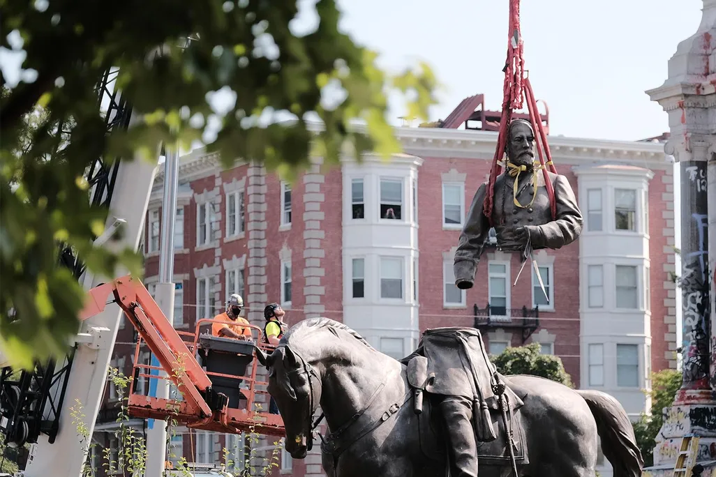 A view of a crane lifting the top of the sculpture, including Lee's torso and arms, off of his legs and horse below