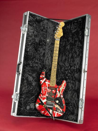Red guitar with black and white accents propped up in guitar case
