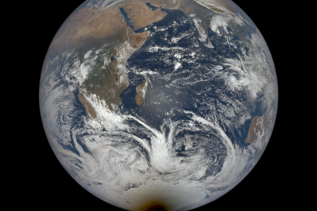 An image of Earth taken from outer space. It shows the whole planet with a dark spot over Antarctica.