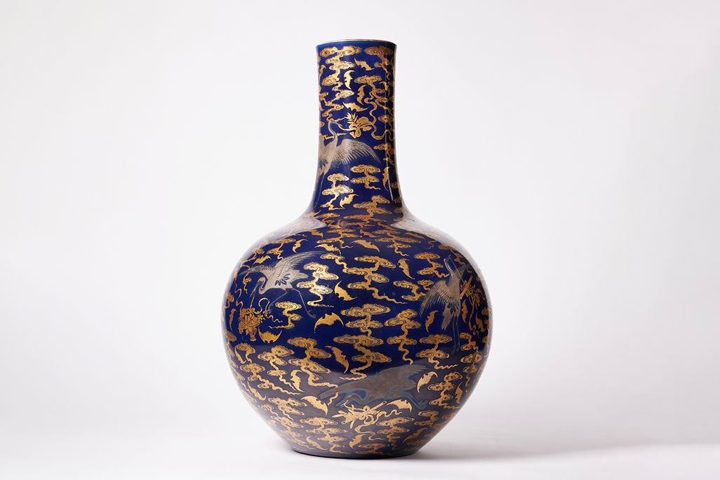 Picture of a blue and gold vase with a round body and thin neck
