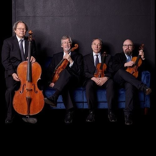 Four men with string instruments pose for a photo