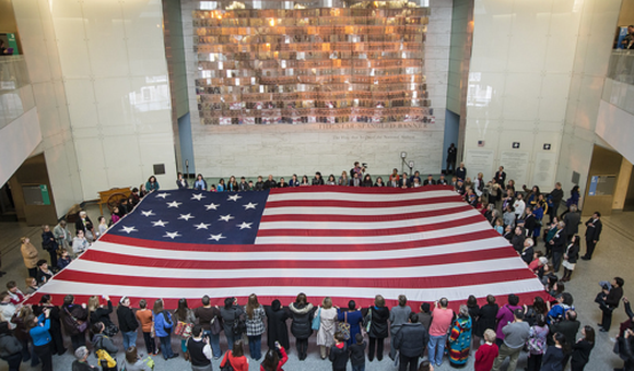 Museum visitors participate in a flag folding while singing (or humming) the anthem (NMAH)