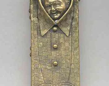 Matchbook in the shape of a folded men’s shirt, with incised checkerboard-patterned weave, cuffs and bib, smiling child’s head peering out from opening at collar. Reverse inscribed “New York Clothing House, 102 & 104 Baltimore St., Baltimore.” Upper curved section swings open to reveal match compartment,  c. mid-19th century.