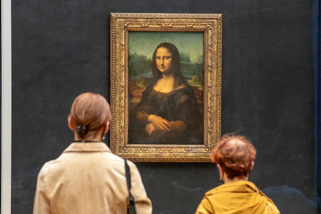 Backs of two peoples' heads as they look at the Mona Lisa