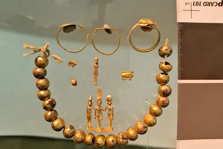 The discoveries include gold-plated beads, eye-shaped amulets and a small statue of three Egyptian gods.