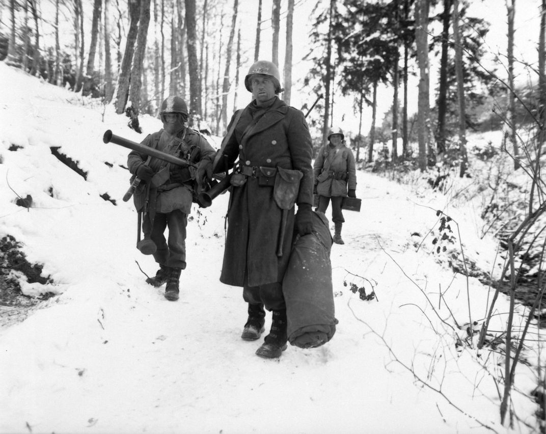 Men wearing military uniforms walking on snowy ground