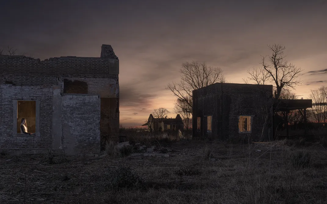 Two houses sit in the desert at sunset