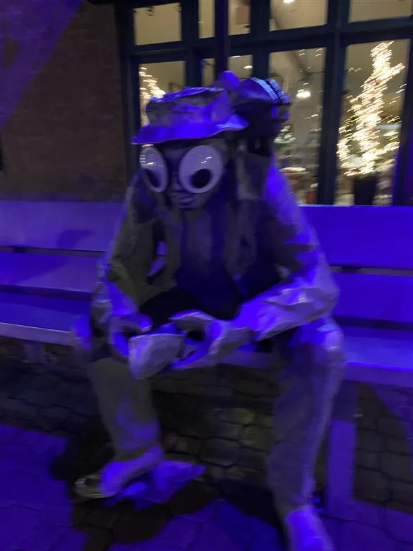 Dark photo of a sculpture of a man sitting on a bench