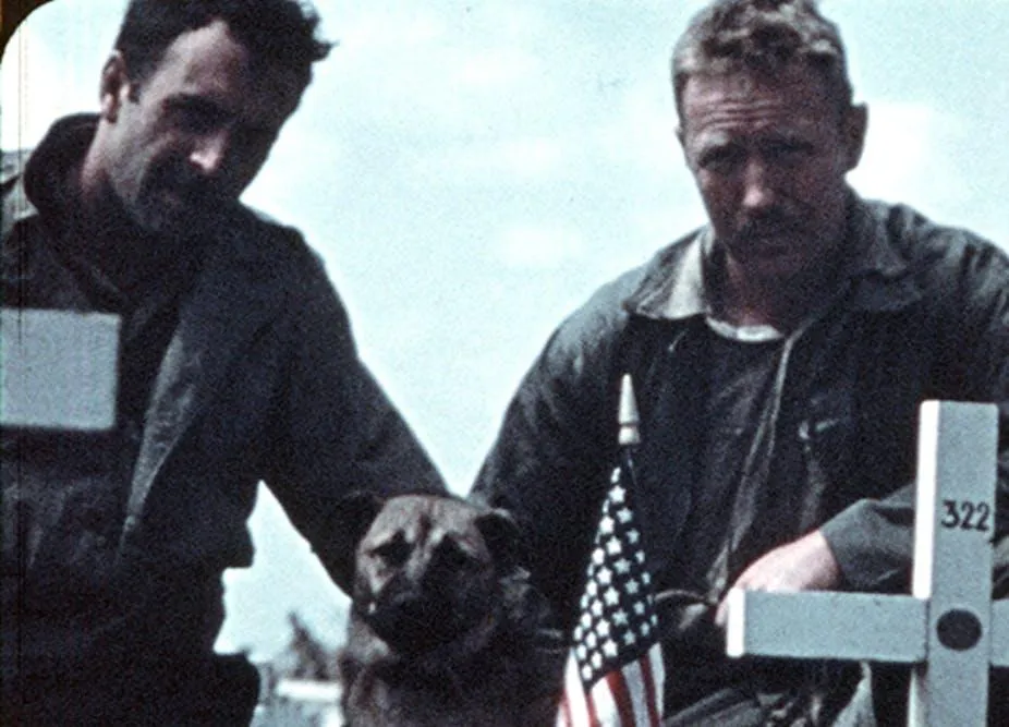 Two Marins near a cross that is inscribed with the number 322
