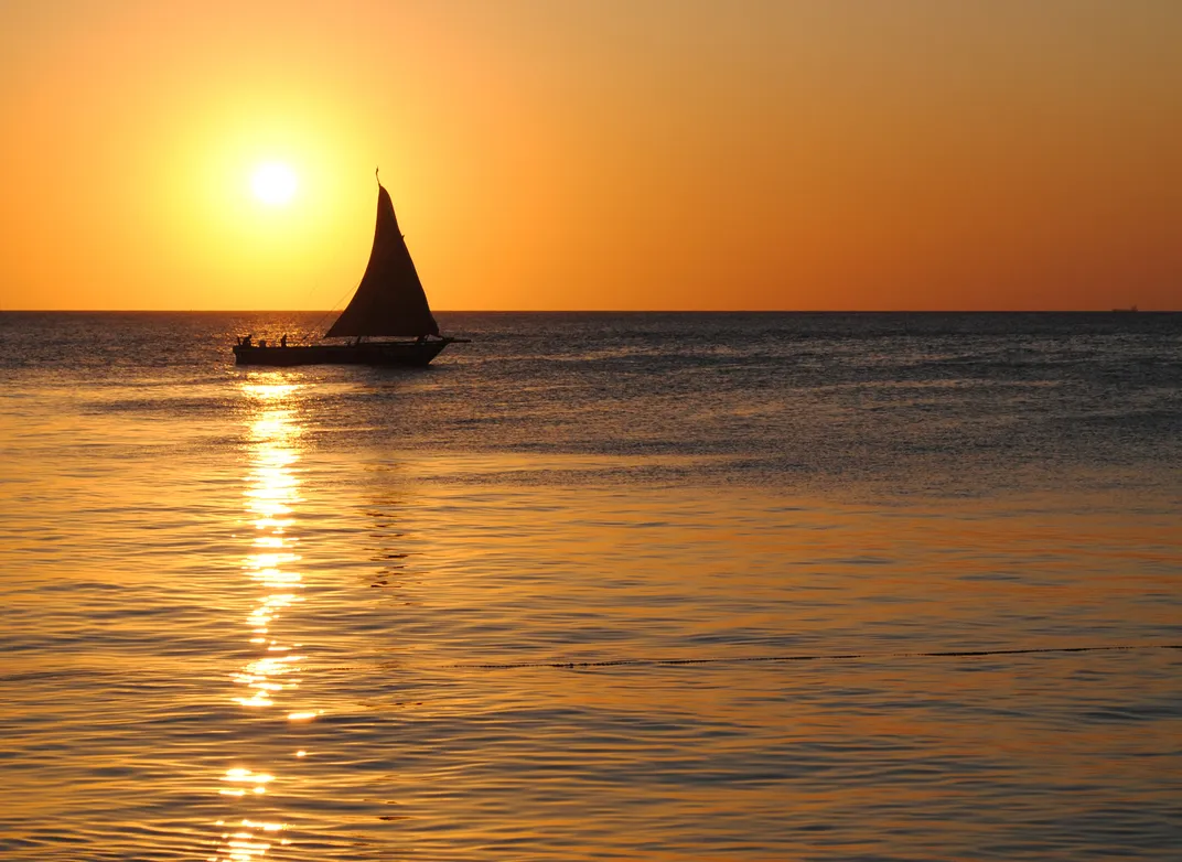 Sunset with traditional <i>dhou</i> on the water off Zanzibar's Stone Town