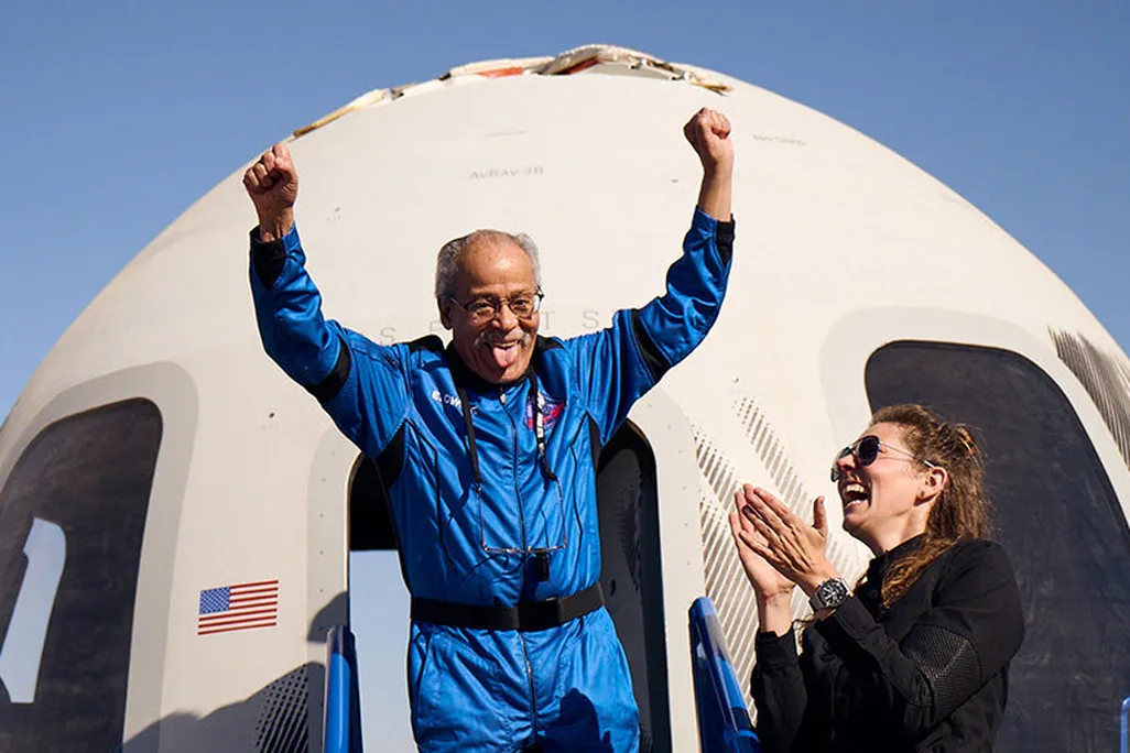 Ed Dwight raises arms outside capsule