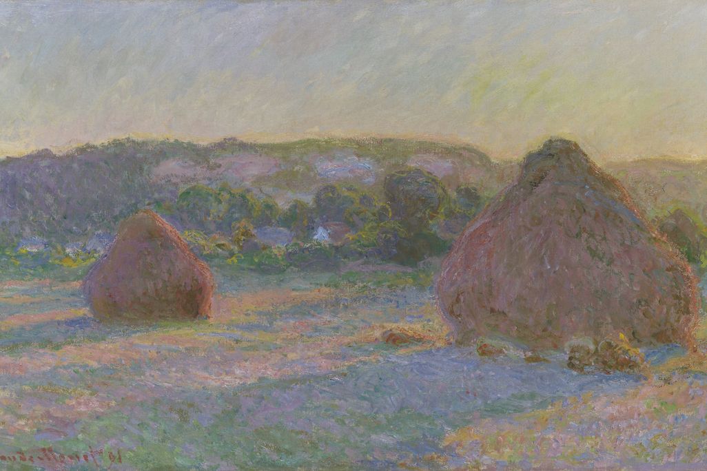 A pinkish field in bluish-yellow light, with one small wheat stack on the left and a larger one, round with a conical top, on the right. It appears to be evening or morning. The stacks leave long purple shadows and the light is hazy