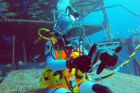 Csilla Ari D’Agostino sits in front of the Aquarius habitat and uses a waterproof iPad for cognitive tests as part of her research on NEEMO 23.