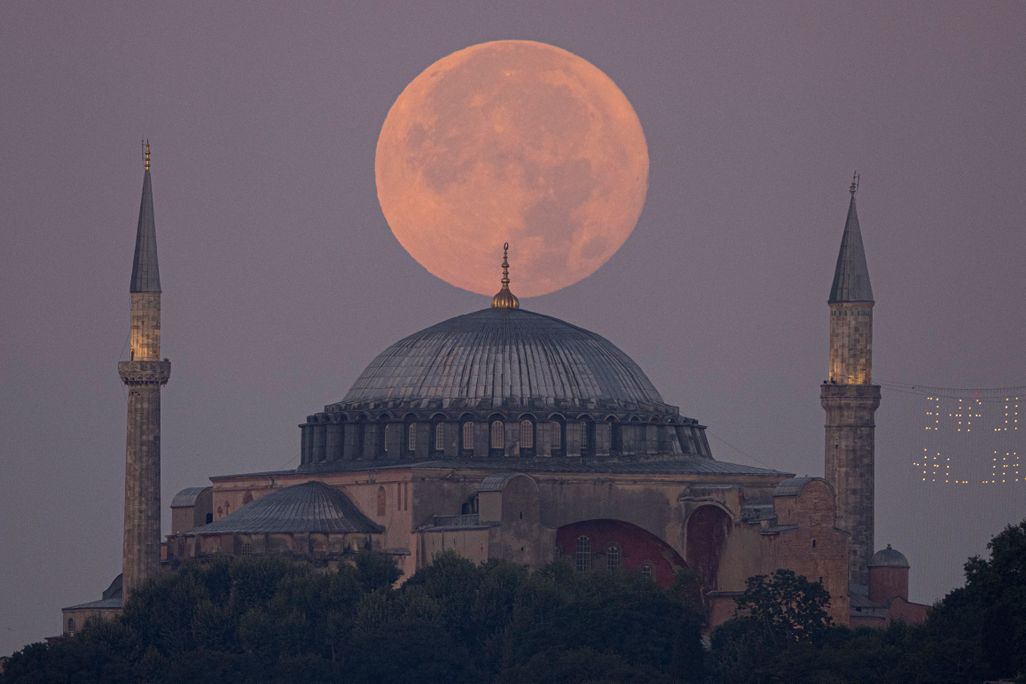 An orange-tinged supermoon sits in the sky directly above the Hagia Sophia Grand Mosque in Istanbul