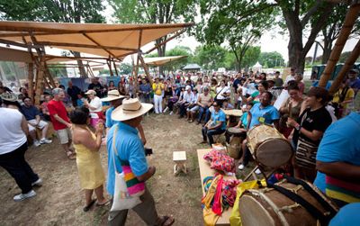 Visitors and artists interact under the guadua (bamboo) tents in the Colombia program area.