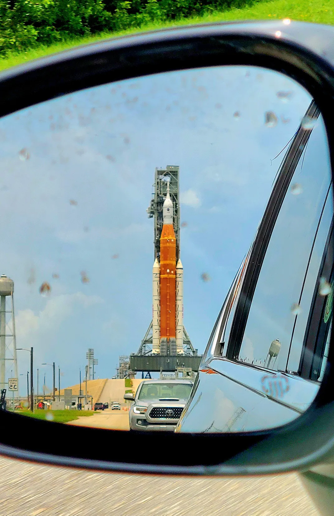 14 - Seen in a car’s side mirror, Artemis 1 stands ready to travel to the moon from Kennedy Space Center’s Launch Complex 39B.