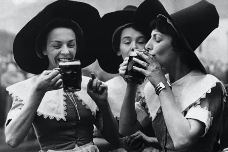 Three women dressed in period garb as alewives. The tall hats became a part of witch iconography.