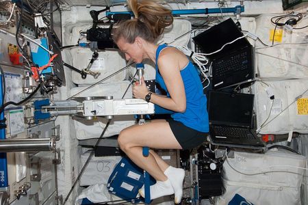 Astronaut Karen Nyberg using the Space Linear Acceleration Mass Measurement Device (SLAMMD) on board the space station.