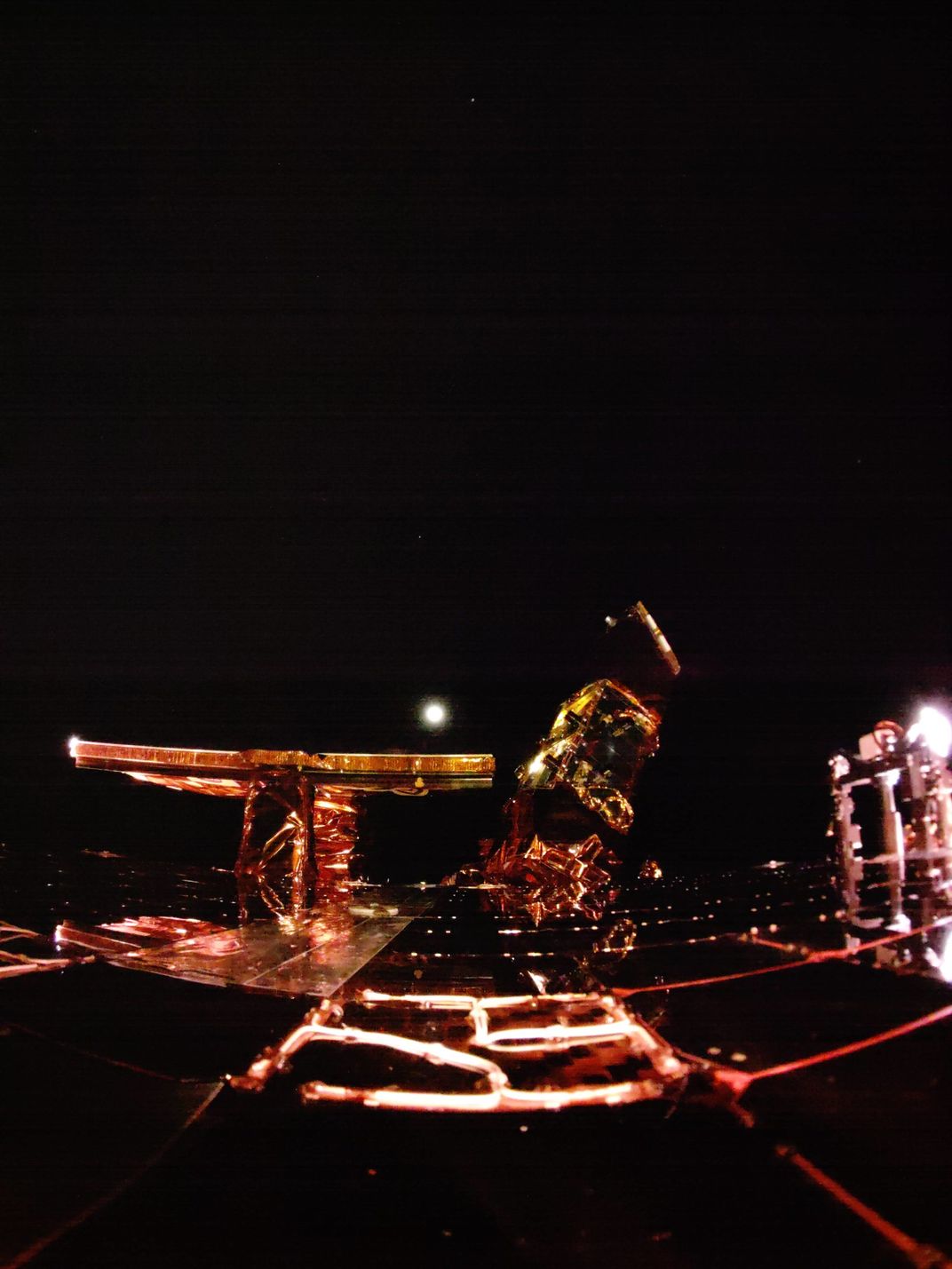 spacecraft hardware with a glowing white orb in the distance