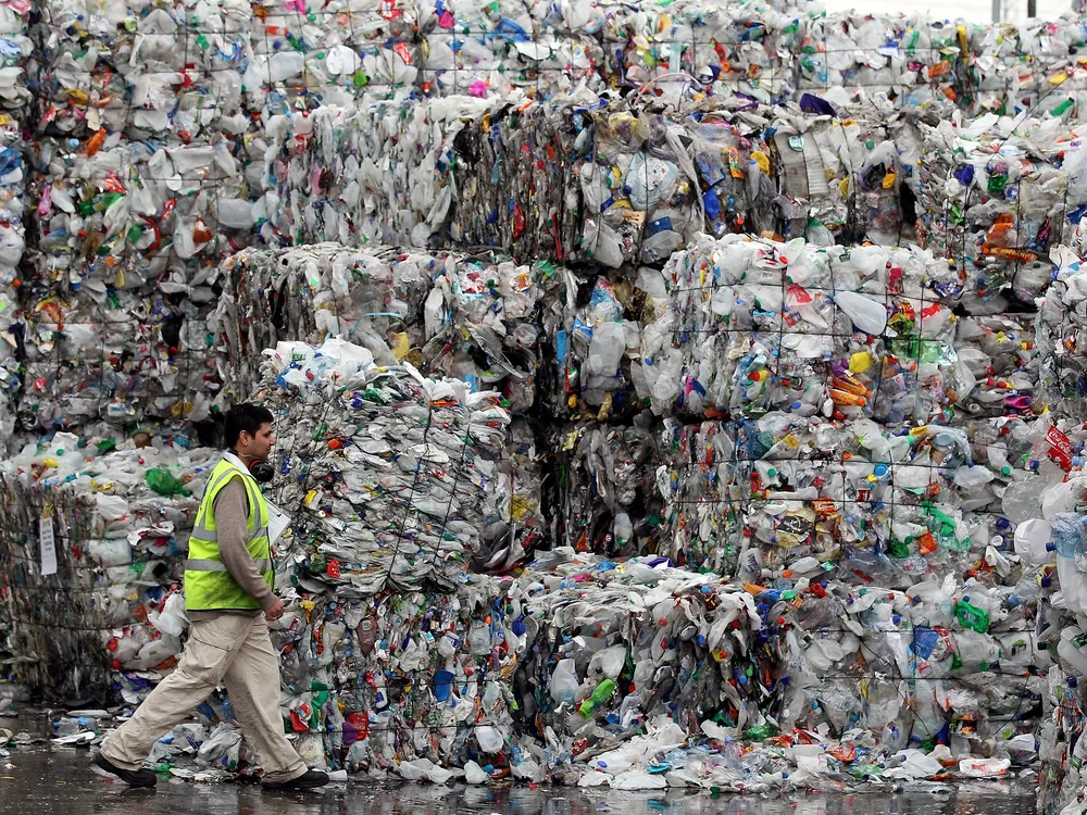 A person dwarfed by stacks of plastic bottles