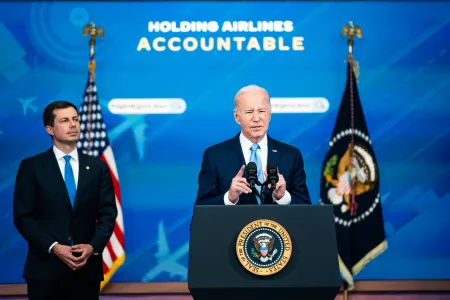 Transportation Secretary Pete Buttigieg listens as President Joe Biden delivers remarks about requiring airlines to compensate passengers for extensive flight delays and cancellations.