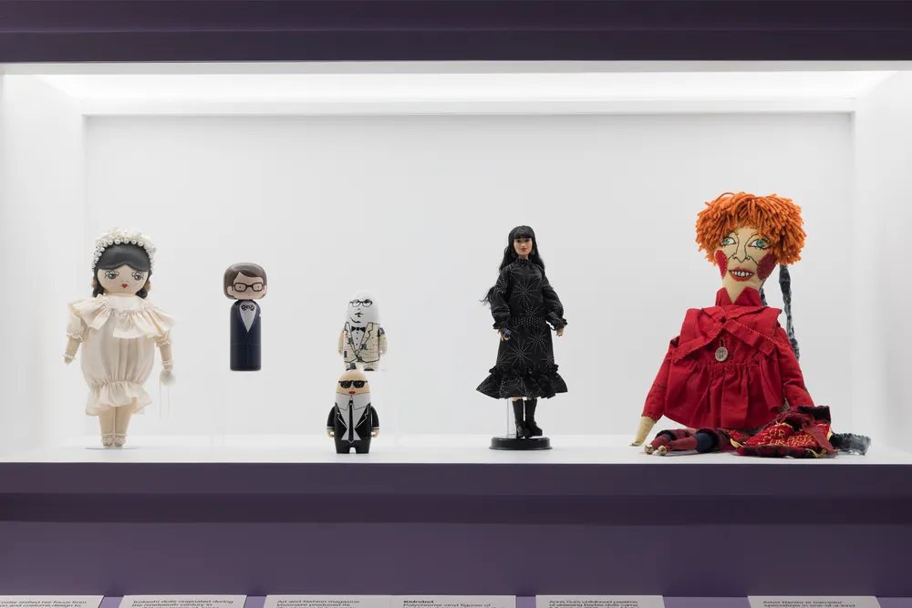 A display case featuring "Dolls as Designers," including Yves Saint Laurent (second from left) and Anna Sui (second from right)