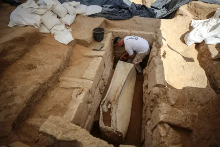 An archaeologist works on the second lead sarcophagus discovered, which is engraved with dolphins.