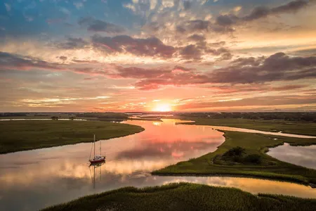 A lone boat sails along the salt marsh at sunset. South Carolina has around 500,000 acres of salt marsh.