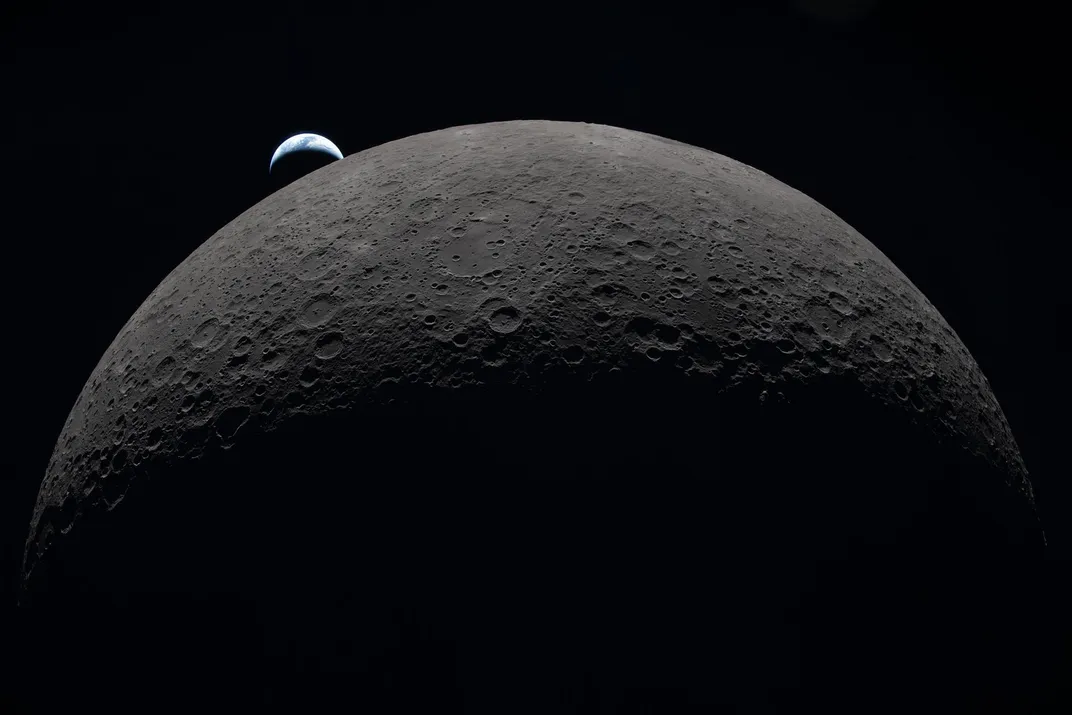 the moon looms large, and a small Earth appears just over its upper left