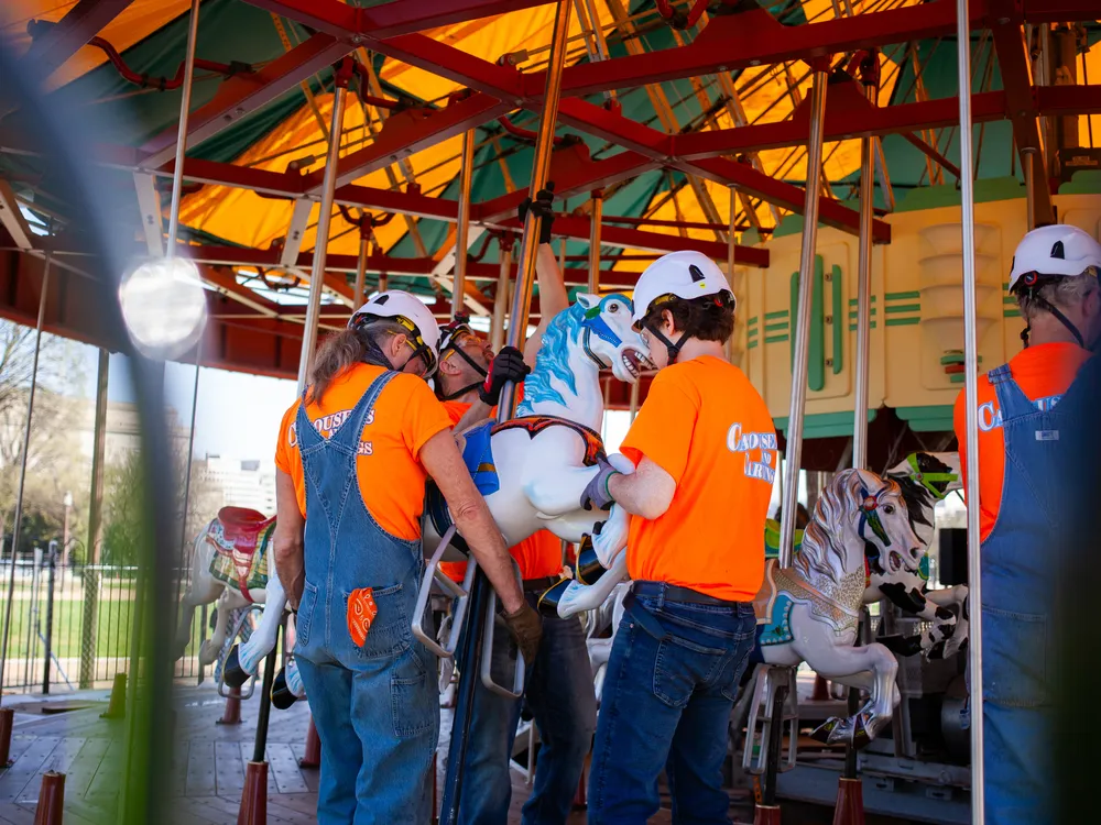 Workers install a horse in the refurbished Smithsonian carousel