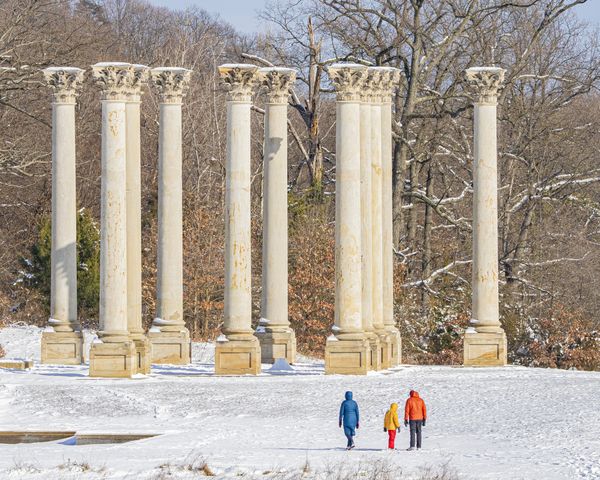 Rainbow-clad family visiting capitol columns in the snow. thumbnail