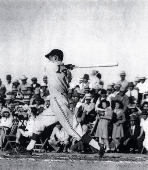 Black and white photo of Testuo Furukawa swinging a baseball bat in front of a small crowd