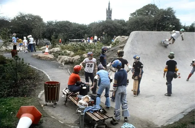 Young people in 1978 wearing helmets and other safety gear skateboarding at Kelvin Wheelies skatepark.