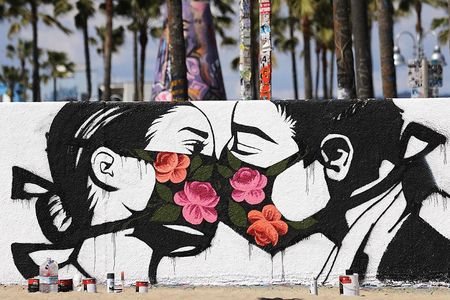 A street art piece by artist Pony Wave depicts two people kissing while wearing face masks on Venice Beach in Venice, California.