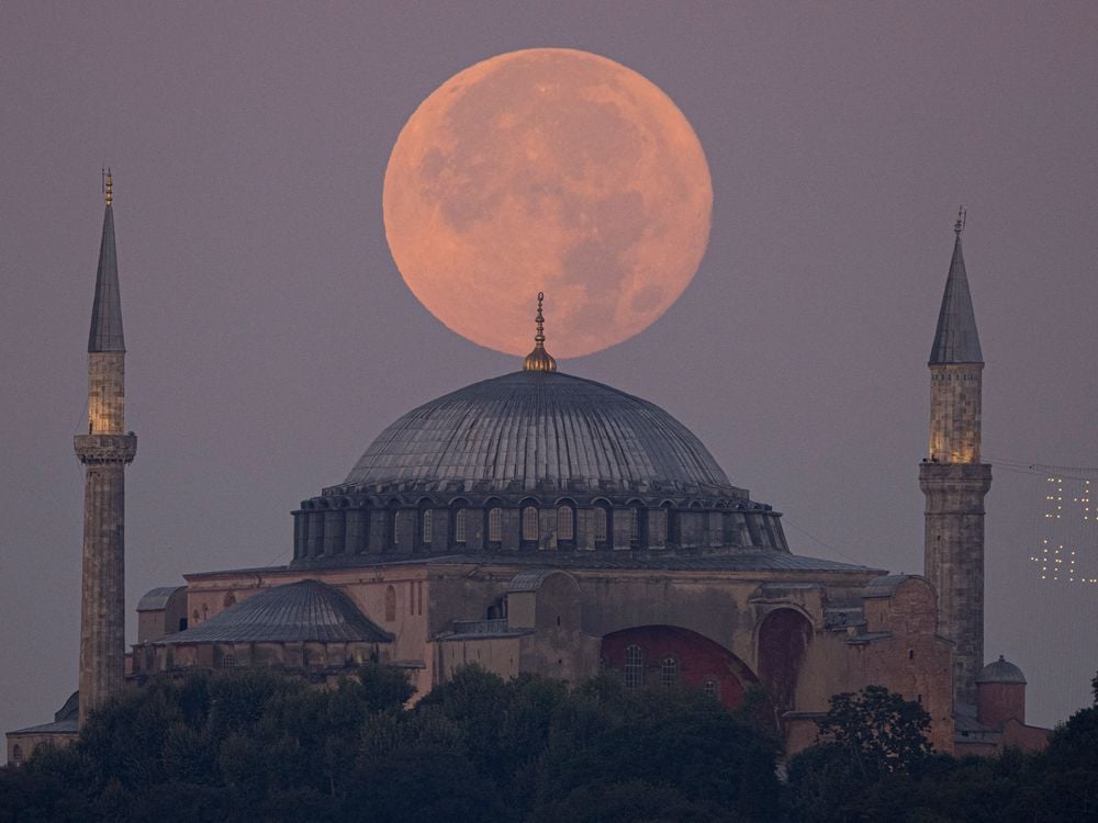 An orange-tinged supermoon sits in the sky directly above the Hagia Sophia Grand Mosque in Istanbul